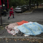
              A member of the rescue service walks past three bodies, covered by blankets, following a Russian attack in Dnipro, Ukraine, Monday, Oct. 10, 2022. Explosions on Monday rocked multiple cities across Ukraine, including missile strikes on the capital Kyiv for the first time in months. (AP Photo/Leo Correa)
            