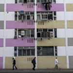 
              People walk past public housing buildings in Hong Kong, Wednesday, Oct. 19, 2022. Hong Kong's leader on Wednesday unveiled a new visa scheme to woo global talent, as the city seeks to stem a brain drain that has risked its status as an international financial center. (AP Photo/Vernon Yuen)
            