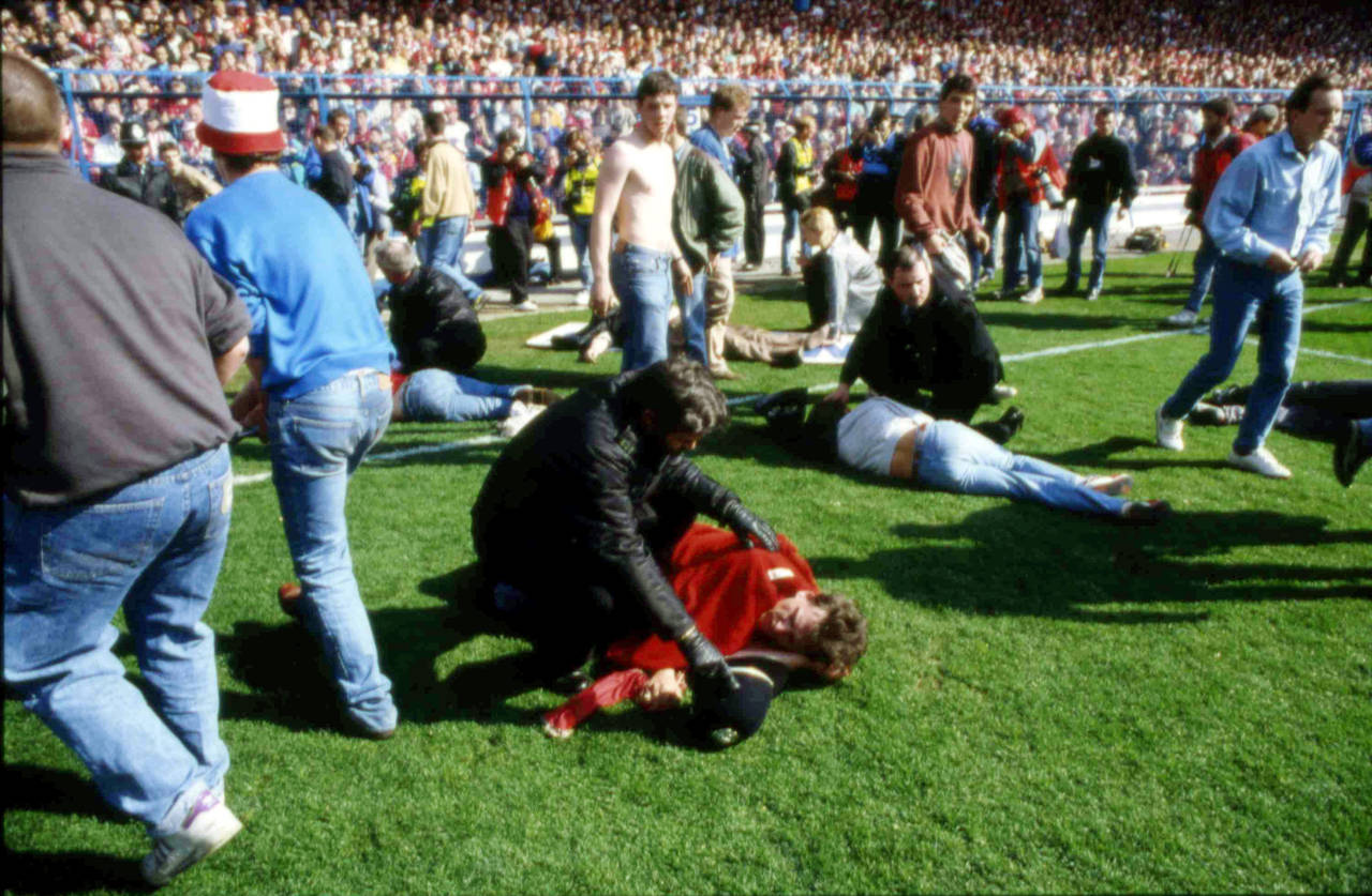 FILE - Stewards and supporters tend and care for wounded supporters on the field at Hillsborough St...