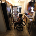 
              India Scott looks in her refrigerator in her home in New Orleans, Monday, Oct. 10, 2022. Activists, advocates, researchers and people living with disabilities say not enough is being done to include disabled people in climate action planning and policy, or disaster relief and recovery efforts. (AP Photo/Gerald Herbert)
            