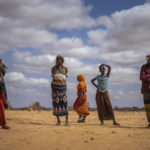 
              Men and women stand at a camp for displaced people on the outskirts of Dollow, Somalia, on Monday, Sept. 19, 2022.  Somalia is in the midst of the worst drought anyone there can remember. A rare famine declaration could be made within weeks. Climate change and fallout from the war in Ukraine are in part to blame. (AP Photo/Jerome Delay)
            