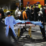 
              Rescue workers carry a victim on the street near the scene in Seoul, South Korea, Sunday, Oct. 30, 2022. Scores of people were killed and others were injured as they were crushed by a large crowd pushing forward on a narrow street during Halloween festivities in the capital, South Korean officials said. (AP Photo/Lee Jin-man)
            
