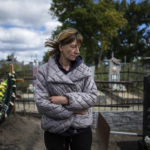 
              Olha Zaparozhchenko stands near the grave of her brother Ivan Shabelnyk, left, in the recently liberated village of Kapitolivka near Izium, Ukraine, Sunday, Sept. 25, 2022. Shabelnyk's hands were shot, his ribs broken, his face unrecognizable. They identified him by the jacket he wore, from the local grain factory where he worked. (AP Photo/Evgeniy Maloletka)
            