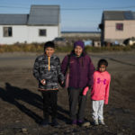 
              Ardith Weyiouanna, center, holds the hand of her grandchildren, Isaac Olanna, left, and Kyle Rose Olanna as they stand for a photo after attending a Sunday service at the Shishmaref Lutheran Church in Shishmaref, Alaska, Sunday, Oct. 2, 2022. "To move somewhere else, we'd lose a part of our identity. It's hard to see myself living elsewhere," said Weyiouanna, whose family first came to Shishmaref with a dogsled team in 1958. (AP Photo/Jae C. Hong)
            
