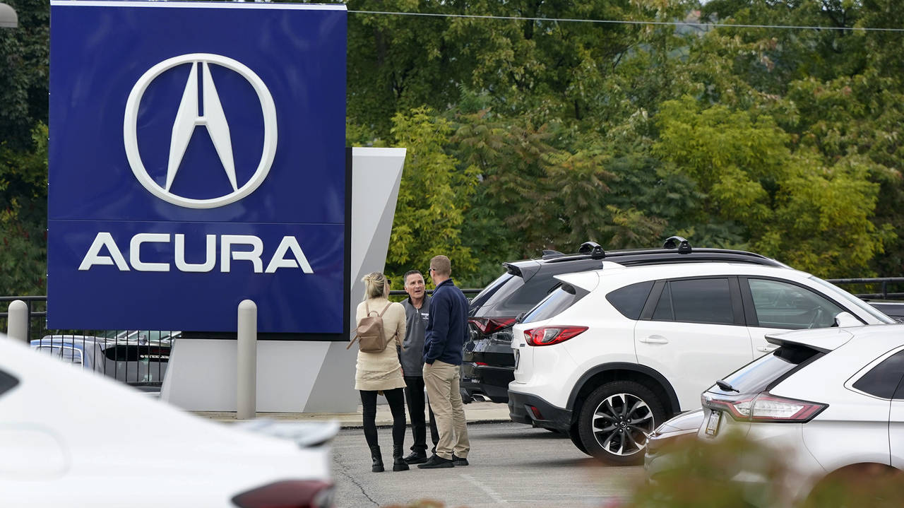 FILE - A salesman talks with customers in an Acura dealership lot in Wexford, Pa., on Sept. 29, 202...