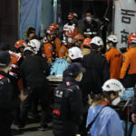 
              Rescue workers carry a victim on the street near the scene in Seoul, South Korea, Sunday, Oct. 30, 2022. Scores of people were killed and others were injured as they were crushed by a large crowd pushing forward on a narrow street during Halloween festivities in the capital, South Korean officials said.  (AP Photo/Lee Jin-man)
            