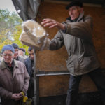 
              A volunteer unloads bread as local residents wait for free bread distribution in Bakhmut, the site of the heaviest battle against the Russian troops in the Donetsk region, Ukraine, Friday, Oct. 28, 2022. (AP Photo/Efrem Lukatsky)
            