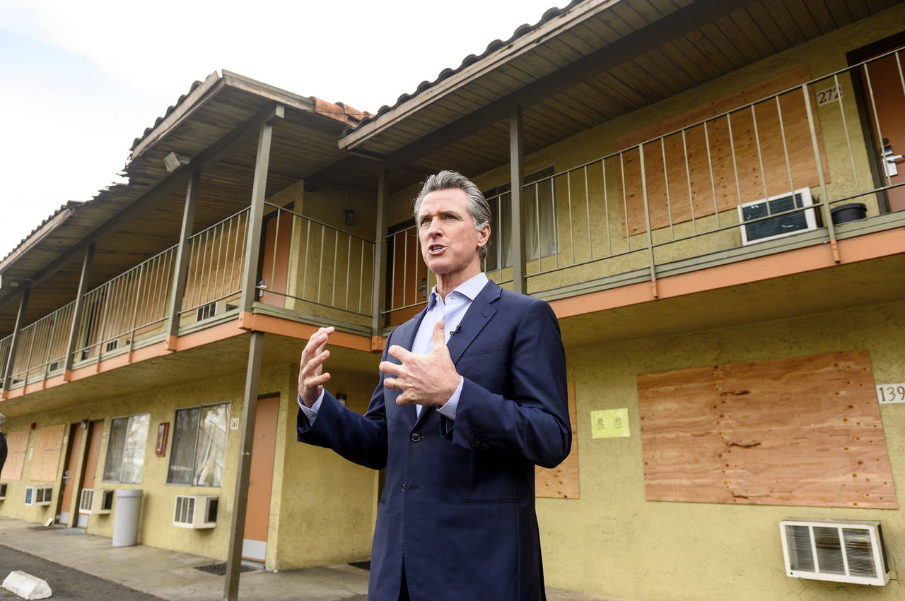 FILE - California Governor Gavin Newsom speaks with reporters while touring an inn being converted ...