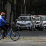 
              A woman rides past police vehicles parked along a road monitoring near the site of last weekend protest in Beijing, Tuesday, Nov. 29, 2022. With police out in force, there was no word of protests Tuesday in Beijing, Shanghai or other major cities. (AP Photo/Andy Wong)
            