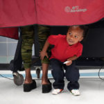 
              Kash Strong, 3, peeks out from under the curtain of a voting booth as his mother Sophia Amacker casts her vote on Election Day at the Martin Luther King Elementary School in the Lower Ninth Ward of New Orleans, Tuesday, Nov. 8, 2022. (AP Photo/Gerald Herbert)
            