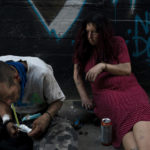 
              Jenn Bennett, who is high on fentanyl, sits on her skateboard with a visible black eye as her friend, Jesse Williams, smokes the drug in Los Angeles, Tuesday, Aug. 9, 2022. Use of fentanyl, a powerful synthetic opioid that is cheap to produce and is often sold as is or laced in other drugs, has exploded. Because it's 50 times more potent than heroin, even a small dose can be fatal. It has quickly become the deadliest drug in the nation, according to the Drug Enforcement Administration. Two-thirds of the 107,000 overdose deaths in 2021 were attributed to synthetic opioids like fentanyl, the U.S. Centers for Disease Control and Prevention says. (AP Photo/Jae C. Hong)
            