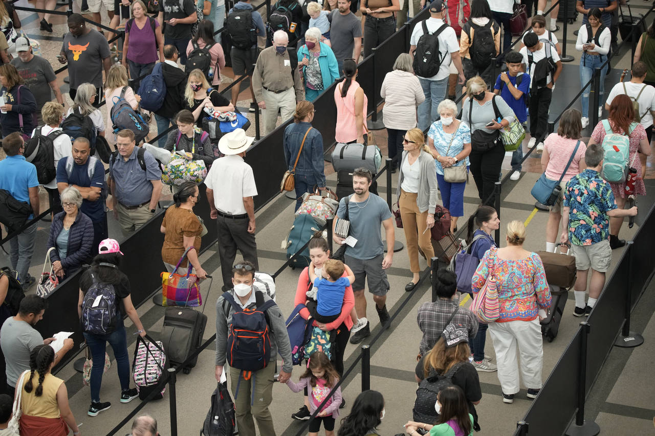 FILE - Travelers queue up at the south security checkpoint in Denver International Airport as the L...