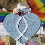 
              Hand-written messages cover the heart attached to the cross to honor a victim of the mass shooting at a gay nightclub at a makeshift memorial near the scene of the crime Wednesday, Nov. 23, 2022, in Colorado Springs, Colo.  The alleged shooter facing possible hate crime charges in the fatal shooting of five people at a Colorado Springs gay nightclub is scheduled to make their first court appearance Wednesday from jail after being released from the hospital a day earlier.  (AP Photo/David Zalubowski)
            