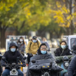 
              Commuters wearing face masks ride along a street in Beijing, Wednesday, Nov. 16, 2022. Chinese authorities locked down a major university in Beijing on Wednesday after finding one COVID-19 case as they stick to a "zero-COVID" approach despite growing public discontent. (AP Photo/Mark Schiefelbein)
            