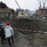 
              Children look at a crater created by an explosion in a residential area after Russian shelling in Solonka, Lviv region, Ukraine, Wednesday, Nov. 16, 2022. (AP Photo/Mykola Tys)
            