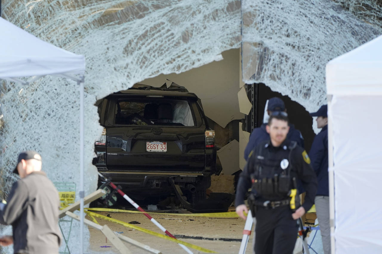 An SUV rests inside an Apple store behind a large hole in the glass front of the store, Monday, Nov...