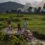 
              FILE - Smoke rises from a coal-powered steel plant in the background as village girls get ready after taking a bath in a stream at Hehal village near Ranchi, in eastern state of Jharkhand, Sept. 26, 2021. Loss and damage is the human side of a contentious issue that will likely dominate climate negotiations in Egypt. (AP Photo/Altaf Qadri, File)
            
