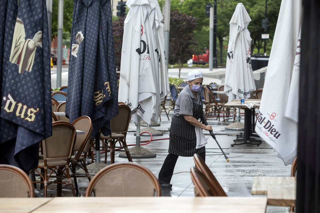 FILE - A worker at a restaurant along K Street in downtown Washington, power washes the outdoor sea...
