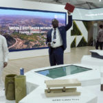 
              Delegates walk through the Saudi Arabia pavilion with a display for the kingdom's Middle East Green Initiative at the COP27 U.N. Climate Summit, Thursday, Nov. 10, 2022, in Sharm el-Sheikh, Egypt. (AP Photo/Nariman El-Mofty)
            