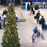 
              A family passes a Christmas tree while checking their bags for a flight at Logan International Airport, Monday, Nov. 21, 2022, in Boston. Travel experts say the ability of many people to work remotely is letting them take off early for Thanksgiving or return home later. Crowds are expected to rival those of 2019, the last Thanksgiving before the pandemic. (AP Photo/Charles Krupa)
            