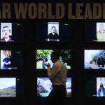
              A man walks past a display of videos addressed to world leaders at the COP27 U.N. Climate Summit, Saturday, Nov. 19, 2022, in Sharm el-Sheikh, Egypt. (AP Photo/Peter Dejong)
            