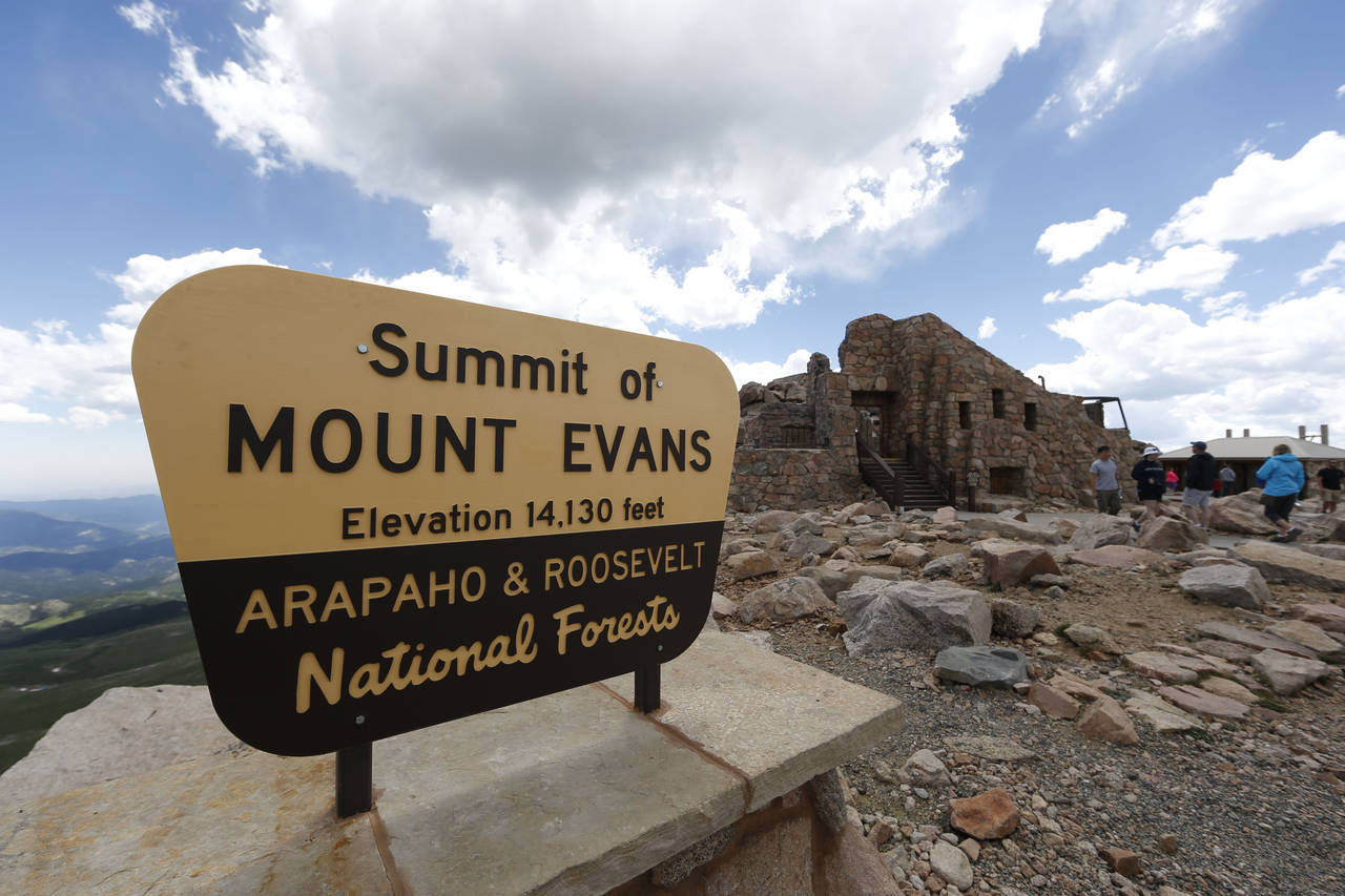 FILE-- Visitors pass the sign on the summit of Mount Evans near Idaho Springs, Colo., on July 15, 2...