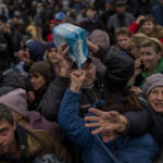 
              Residents gathering at an aid distribution point receive supplies in downtown Kherson, southern Ukraine, Friday, Nov. 18, 2022. (AP Photo/Bernat Armangue)
            