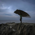 
              FILE - A villager carries material salvaged from his home before it was washed away by erosion of the river Brahmaputra at Murkata village, northeastern Assam state, India, Oct. 9, 2022. India officially takes up its role as chair of the Group of 20 leading economies for the coming year Thursday, Dec. 1 and it's putting climate at the top of the group's priorities. (AP Photo/Anupam Nath, File)
            