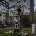 
              Firefighters remove Russian posters in Kherson, in southern Ukraine, on Thursday, November 17, 2022. (AP Photo/Bernat Armangue)
            