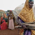 
              Nurto Hassan, right, carries firewood to cook for her children, as other women displaced by the drought look on, at a camp for the displaced on the outskirts of Baidoa, in Somalia Saturday, Oct. 29, 2022. Ships loaded with grain departed Ukraine on Tuesday, Nov. 1, 2022 despite Russia suspending its participation in a U.N.-brokered deal that ensures safe wartime passage of critical food supplies meant for parts of the world struggling with hunger such as Somalia. (AP Photo/Mohamed Sheikh Nor)
            