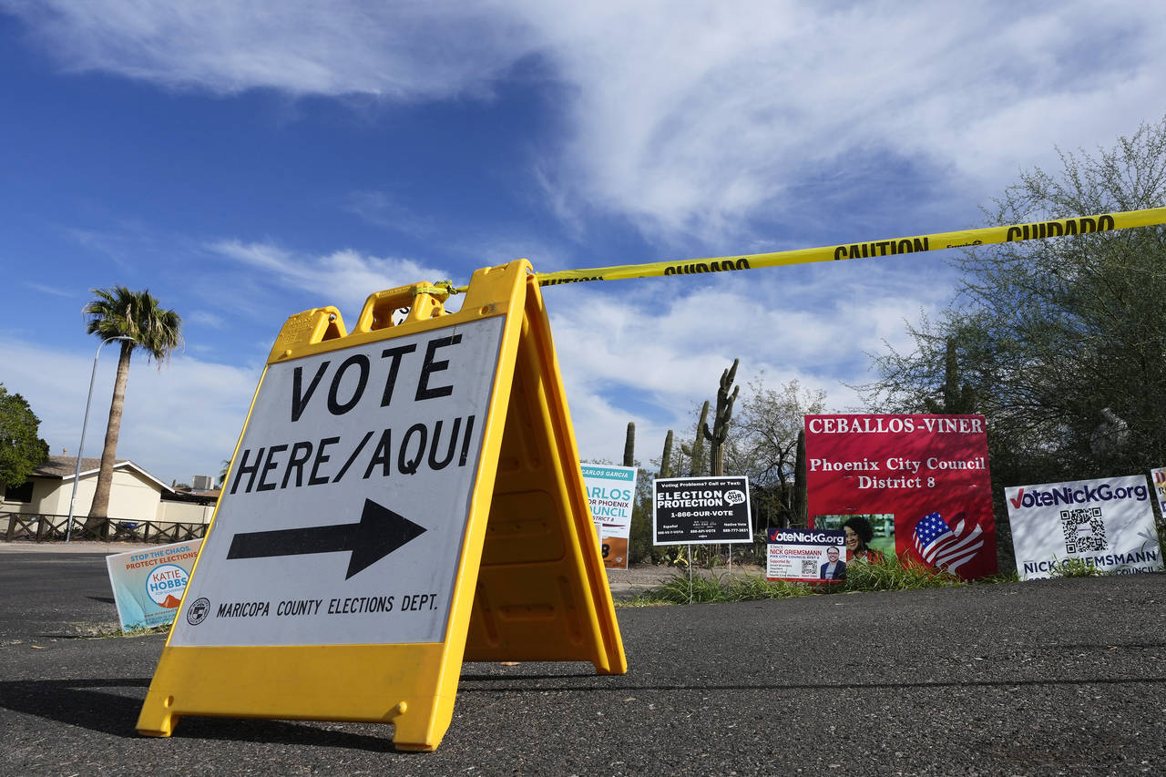 A voting sign points voters in the right direction to drop off ballots in Phoenix, Monday, Nov. 7, ...