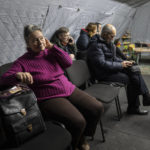 
              People warm themselves and charge their electronic devices in the heating tent "Point of Invincibly" in Kyiv, Ukraine, Monday, Nov. 28, 2022. (AP Photo/Evgeniy Maloletka)
            