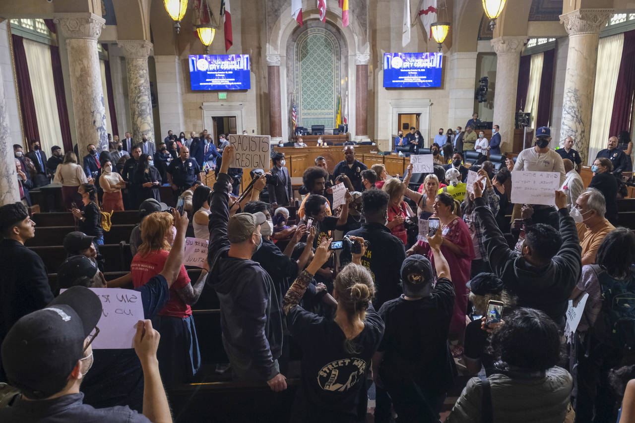 FILE - People hold signs and shout slogans before the cancellation of the Los Angeles City Council ...