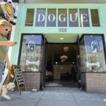 
              CORRECTS DATE TO SUNDAY OCT. 23, 2022 - A pedestrian walks his dog by Dogue, a dog restaurant in San Francisco, Sunday Oct. 23, 2022. Dogue, which rhymes with vogue, just opened up in the city's Mission District. For $75 dollars per pup, doggie diners get a multiple-course "bone appetite" meal featuring dishes like chicken skin waffles and filet mignon steak tartar with quail egg. (AP Photo/Haven Daley)
            