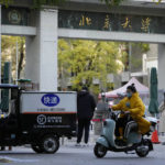 
              A woman wearing mask rides past an entrance to Peking University in Beijing, Wednesday, Nov. 16, 2022. Chinese authorities locked down the major university in Beijing on Wednesday after finding one COVID-19 case as they stick to a "zero-COVID" approach despite growing public discontent. (AP Photo/Ng Han Guan)
            