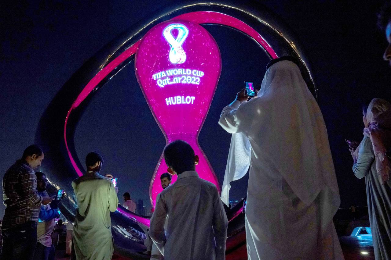 FILE - People take photos with the official FIFA World Cup Countdown Clock on Doha's corniche, in Q...