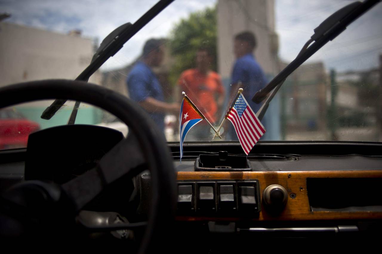 FILE - A Cuban and a U.S. flag hang from the windshield of a car parked in a garage in Havana, Cuba...