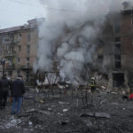 
              People check a damaged building as emergency personnel work at the scene of a Russian shelling in the town of Vyshgorod outside the capital Kyiv, Ukraine, Wednesday, Nov. 23, 2022. Authorities reported power outages in multiple cities of Ukraine, including parts of Kyiv, and in neighboring Moldova after renewed strikes Wednesday struck Ukrainian infrastructure facilities. Multiple regions reported attacks in quick succession, suggesting a barrage of strikes. In several regions, authorities reported strikes on critical infrastructure. (AP Photo/Efrem Lukatsky)
            