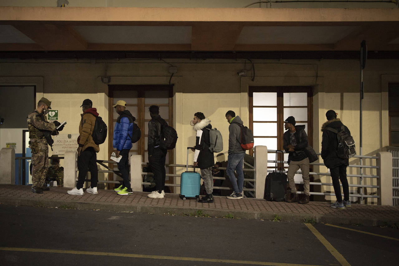 Migrants line up to be checked by Italian authorities at the Italian French border of Ventimiglia, ...