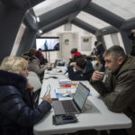 
              A woman speaks to his colleague at the heating tent "Point of Invincibly" in Bucha, Ukraine, Monday, Nov. 28, 2022. (AP Photo/Evgeniy Maloletka)
            