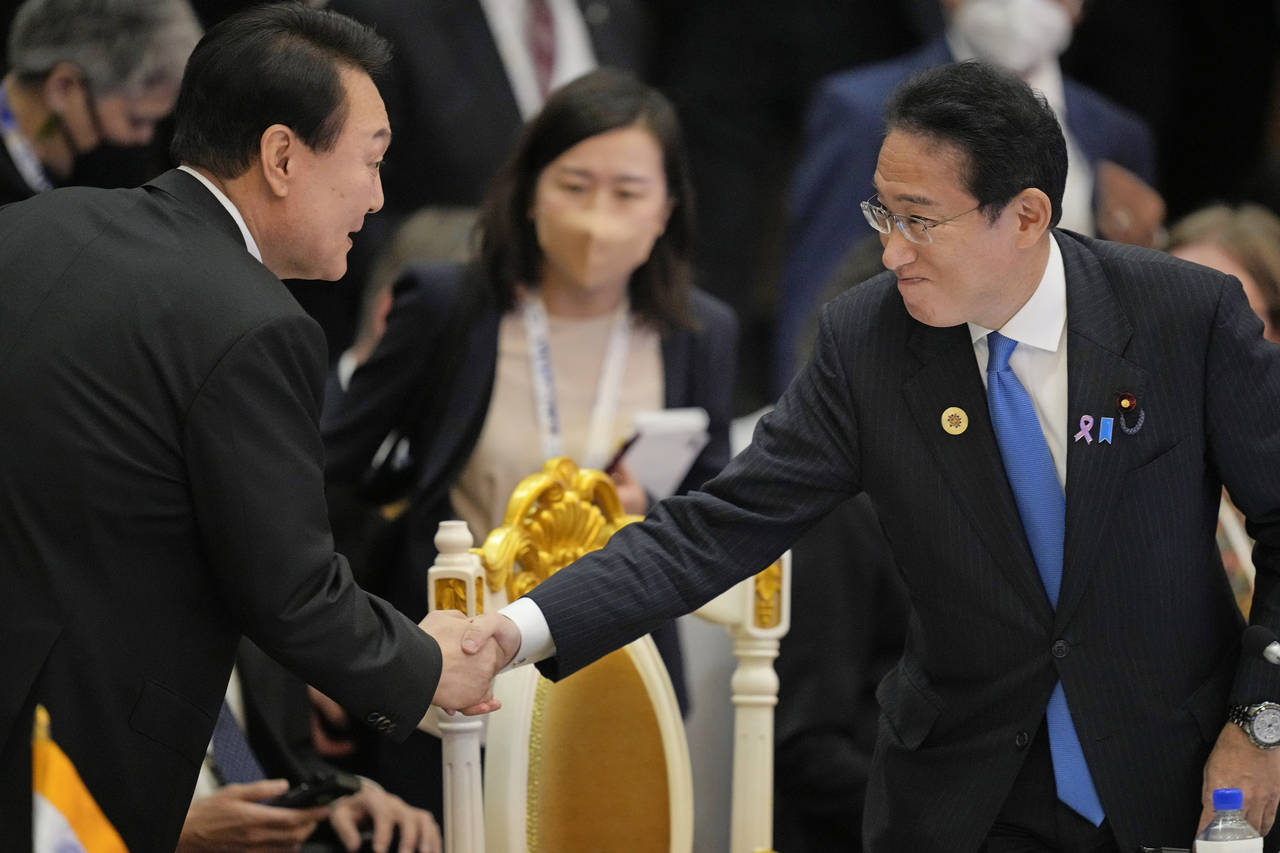 Japan's Prime Minister Fumio Kishida, right, shake hand with South Korea's President Yoon Suk Yeol ...