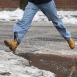 
              A person leaps over a puddle of water and slush as rain falls in Montreal, Friday, Dec. 23, 2022, as a storm system bears down on the region.  (Graham Hughes /The Canadian Press via AP)
            