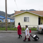
              Brenda López Alvarado, left, and Celia Magdaleno walk to their homes after collecting water from their neighbor's pool following an earthquake in Rio Dell, Calif., Wednesday, Dec. 21, 2022. Water service has not return to the city. (AP Photo/Godofredo A. Vásquez)
            