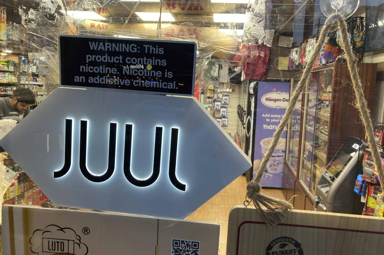 FILE - A Juul sign hangs in the front window of a bodega convenience store in New York City on June...