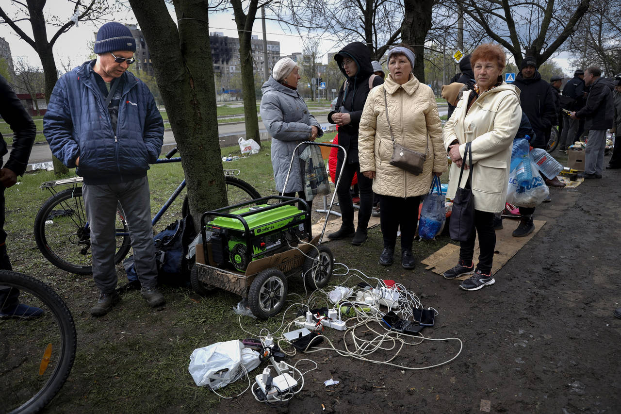 FILE - Local residents gather near a generator to charge their mobile devices in an area controlled...