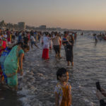 
              People stand in the waters of the Arabian Sea at sunset in Mumbai, India, Saturday, Dec. 31, 2022. (AP Photo/Rafiq Maqbool)
            