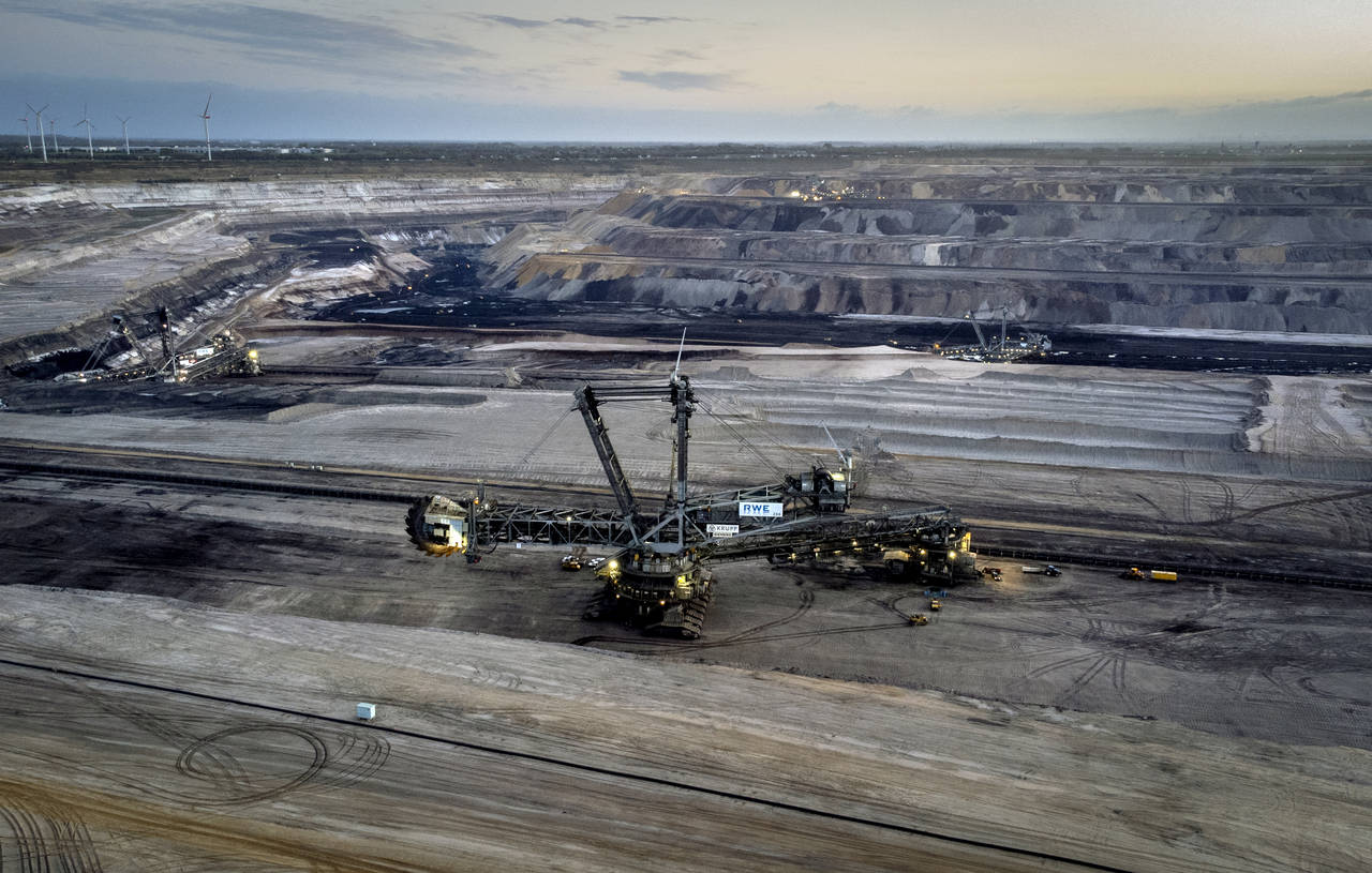 FILE - A bucket wheel excavator is mining coal at the Garzweiler open-cast coal mine with wind turb...