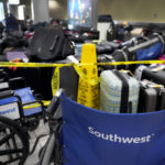 
              Wheelchairs and caution tape restrict access the baggage claim area and piles of luggage inside the Southwest Airlines terminal at St. Louis Lambert International Airport Wednesday, Dec. 28, 2022, in St. Louis. (AP Photo/Jeff Roberson)
            