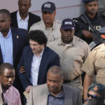 
              FTX founder Sam Bankman-Fried, center left, is escorted out of Magistrate Court into a Corrections van, following a hearing in Nassau, Bahamas, Monday, Dec. 19, 2022. (AP Photo/Rebecca Blackwell)
            