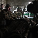 
              Ukrainian servicemen give the first aid to a soldier wounded in a battle with the Russian troops in their shelter in the Donetsk region, Ukraine, Thursday, Dec. 1, 2022. A top adviser to Ukraine's president has cited military chiefs as saying 10,000 to 13,000 Ukrainian soldiers have been killed in the country's nine-month struggle against Russia's invasion, a rare comment on such figures and far below estimates of Ukrainian casualties from Western leaders. Late Thursday, Dec. 1, 2022, Mykhailo Podolyak, a top adviser to Ukrainian President Volodymyr Zelenskyy, relayed new figures about Ukrainian soldiers killed in battle, while noting that the number of injured troops was higher and civilian casualty counts were “significant.” (AP Photo/Roman Chop)
            